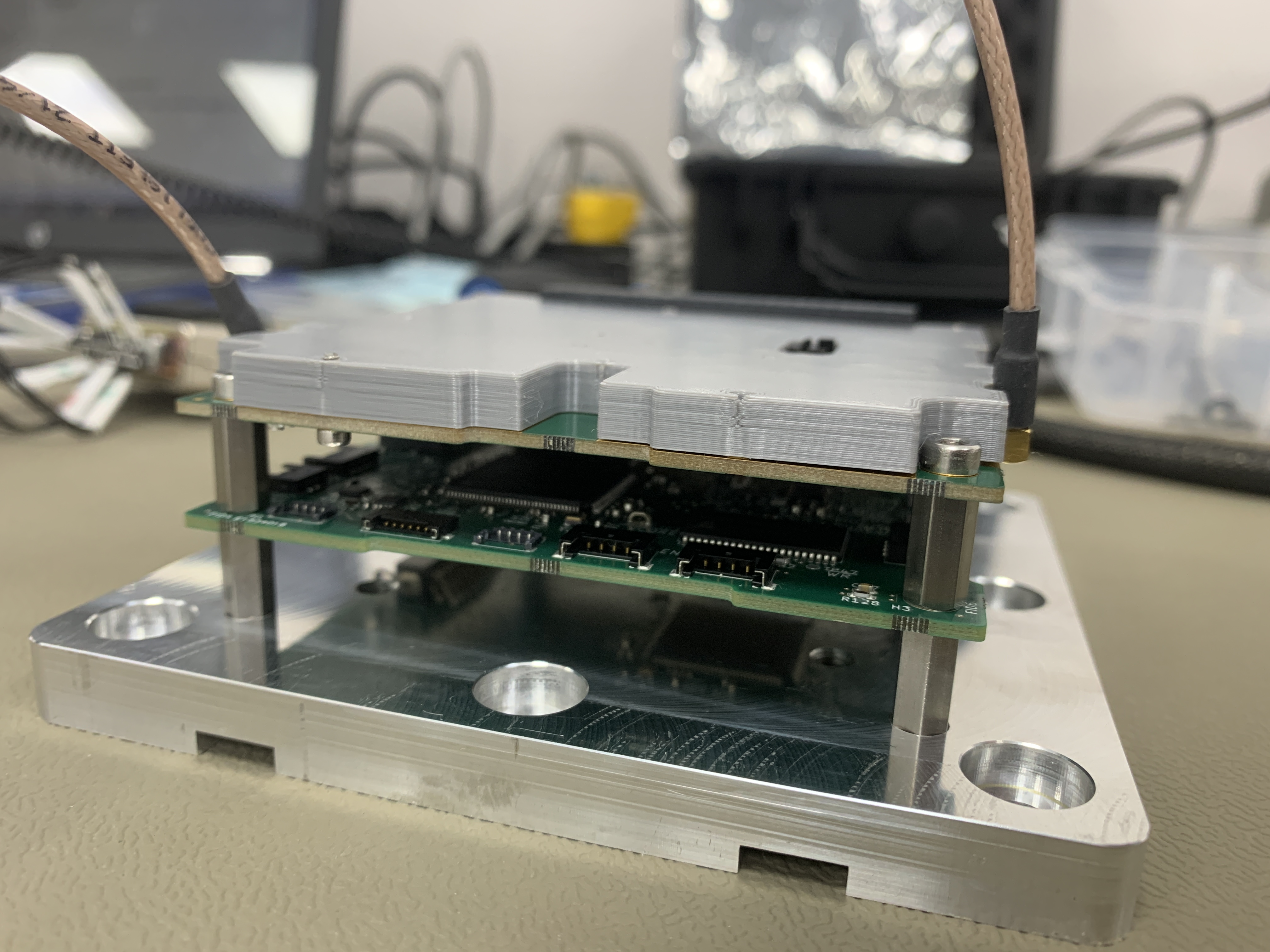 A stack of a two circuit boards, covered by a thick plastic shield, on top of an aluminium plate